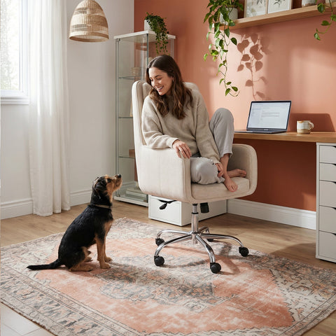 Woman sitting cross-legged in the COLAMY COCOON Beige High-Load Cloud Comfort Swivel Office Chair with a dog beside her in a home office