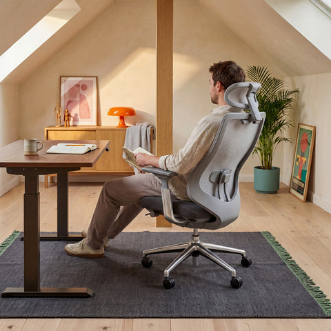 Man Reading in a COLAMY ATLAS Gray Ergonomic High-Back Mesh Office Chair at a Standing Desk in a Home Office